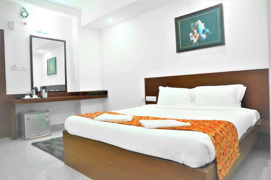 布巴内什瓦尔Harekrishna Hotel & Restaurant的一间卧室配有一张大床和镜子
