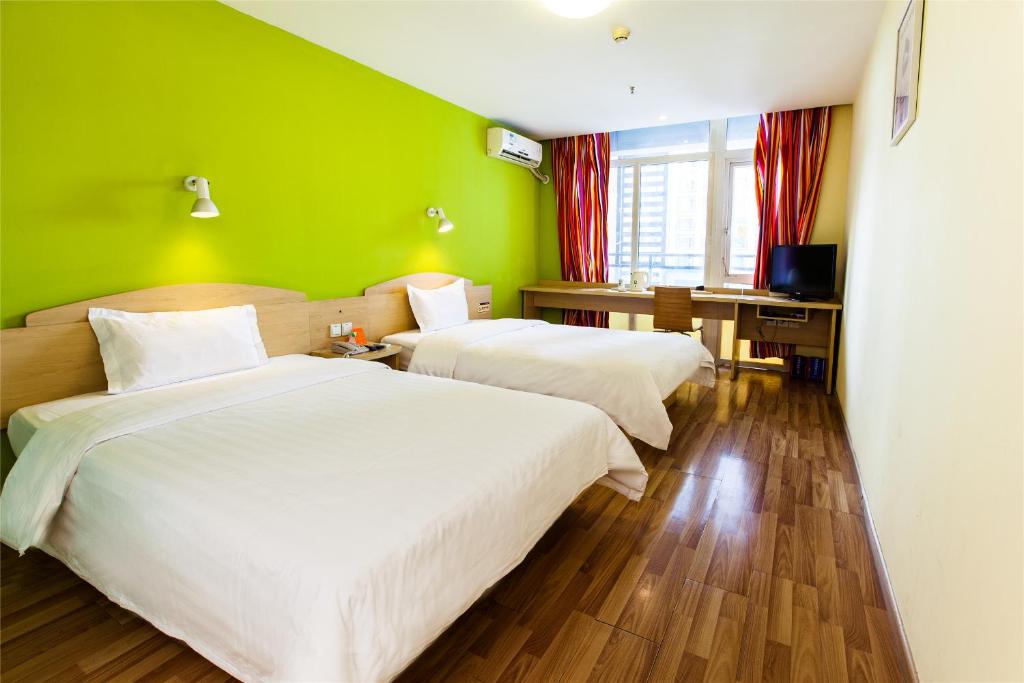 乌鲁木齐7天连锁酒店乌鲁木齐阿勒泰路机场高速店的绿墙客房的两张床