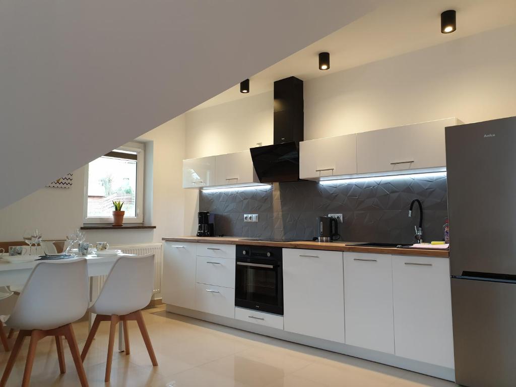 卡尔帕奇VILLA MILA Apartamenty的厨房配有白色橱柜和桌椅