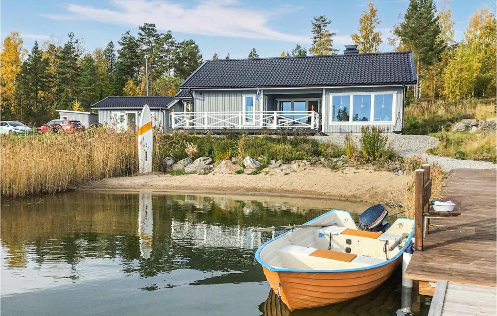 胡迪克斯瓦尔Gorgeous Home In Hudiksvall With Wifi的坐在房子前面的水面上的小船