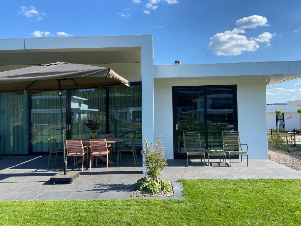 泽沃德Modern villa in Harderwold with garden的庭院配有遮阳伞和桌椅。
