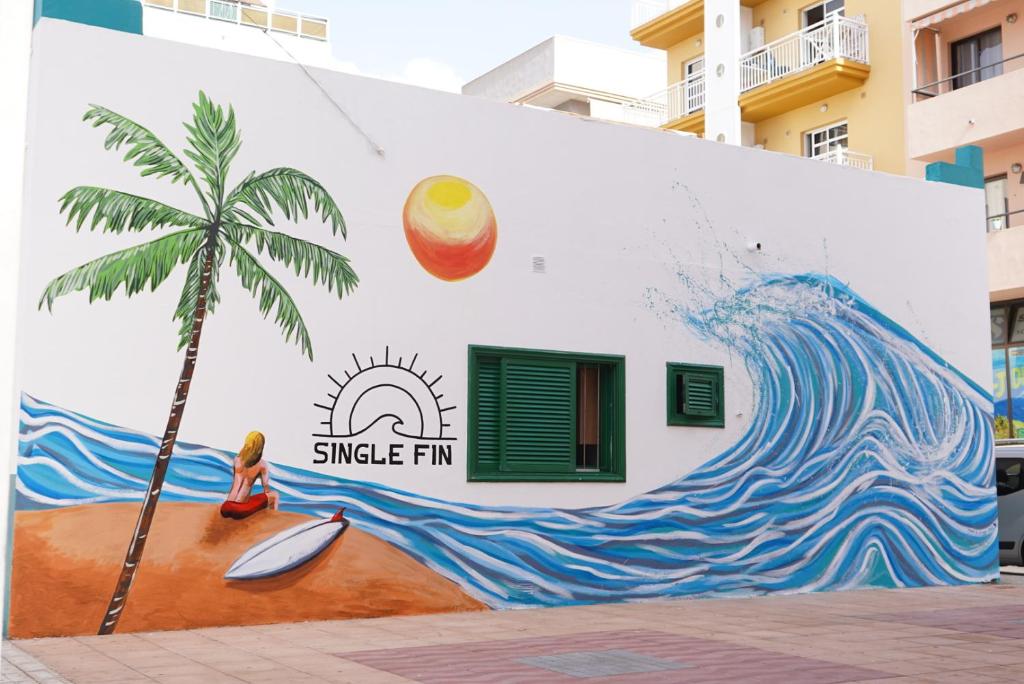 阿罗纳Single Fin Hostel的一座建筑的一侧棕榈树的壁画