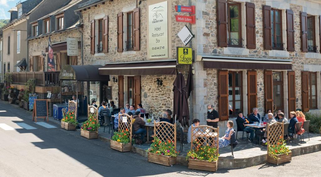 圣谢利多布拉克Logis Hôtel-restaurant Les Coudercous的一群坐在大楼外桌子上的人