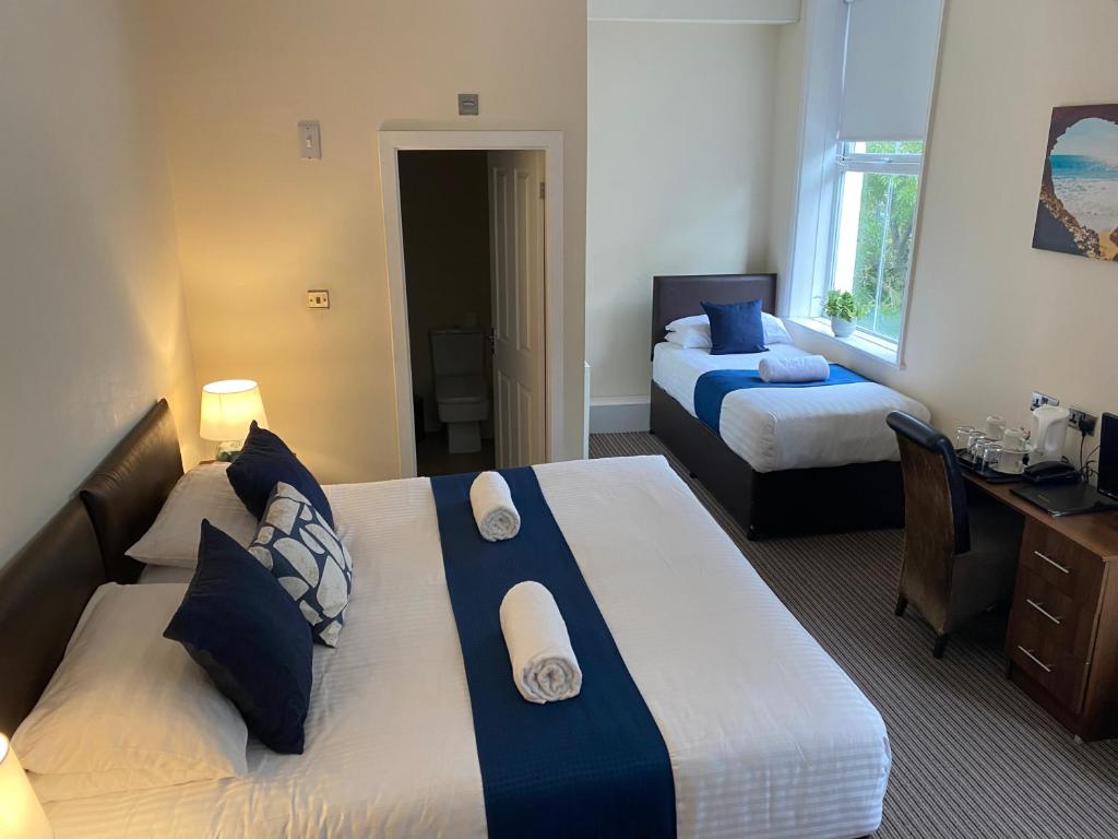 新布赖顿新布赖顿酒店的酒店客房配有两张床、一张书桌和一张书桌。