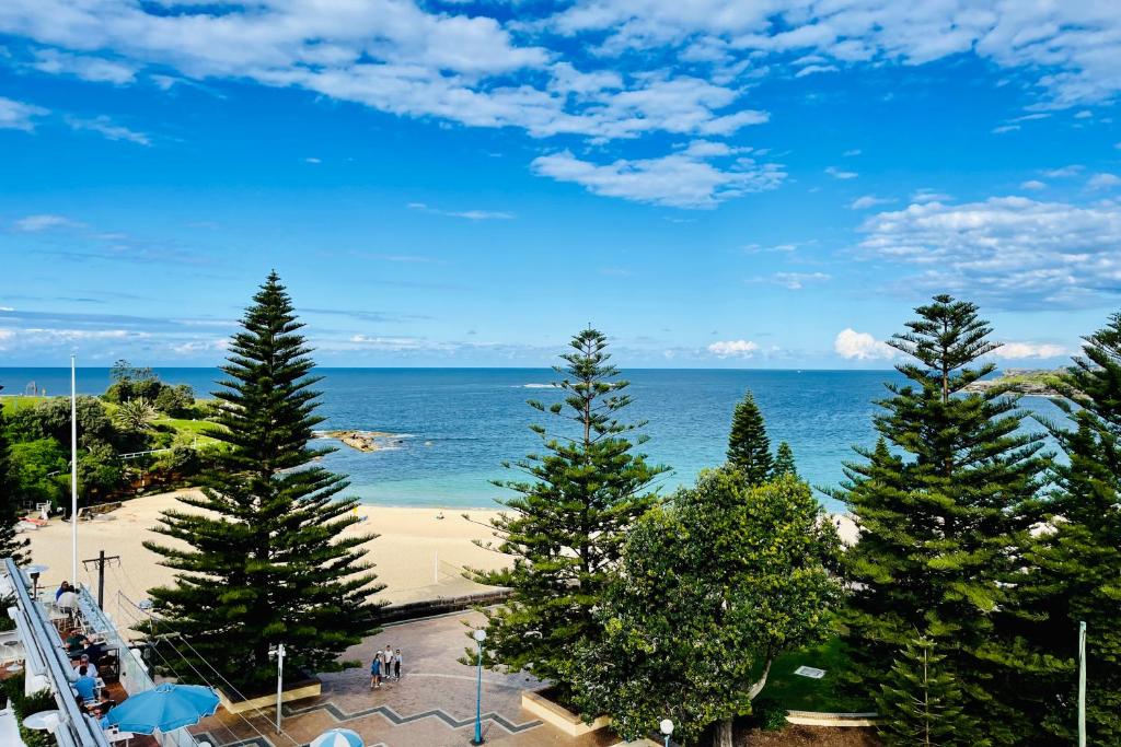 悉尼库吉金沙大酒店和公寓的享有树木繁茂的海滩和大海的景致。