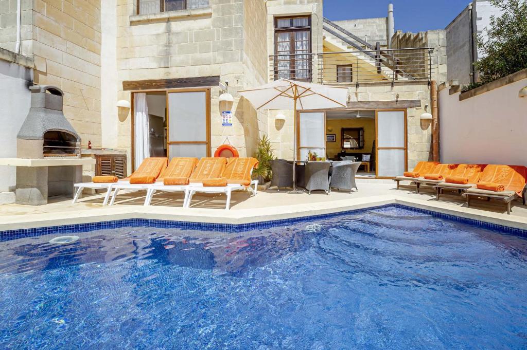 沙拉Razzett Luna Holiday Home的一座房子旁带橙色椅子的大型游泳池