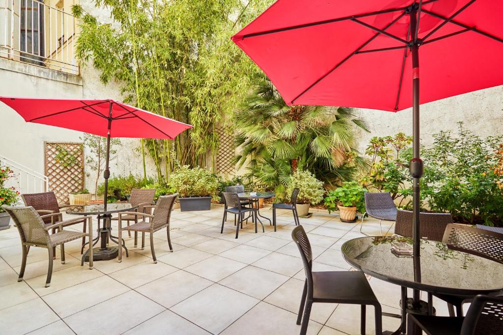 巴黎兰花酒店的一个带桌椅和红伞的庭院