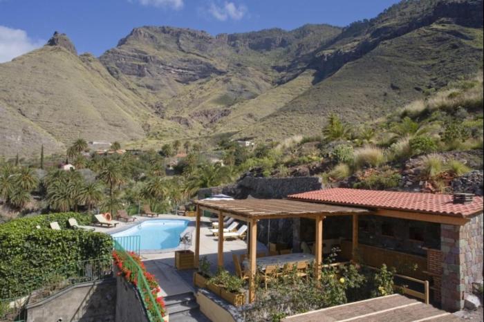 阿格特Casa rural en el Risco de Agaete A的一座房子,后面设有游泳池和山脉
