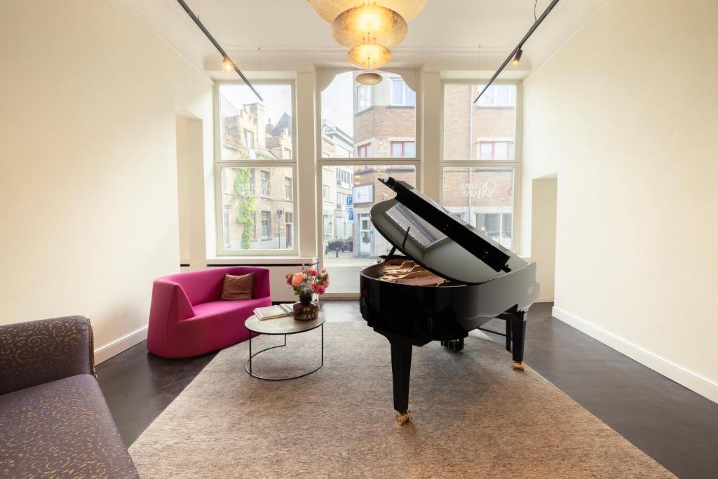 根特B&B Kwaadham 52 - Music Hotel Ghent的客厅里的钢琴和粉色沙发