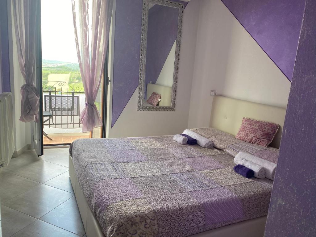 法布罗La Bomboniera di Marco的一间卧室配有一张带紫色墙壁和镜子的床