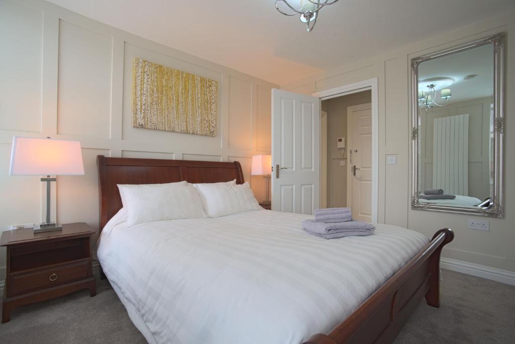 邓斯特布尔Harper Luxe Serviced Apartments Dunstable的卧室配有一张带镜子的白色大床