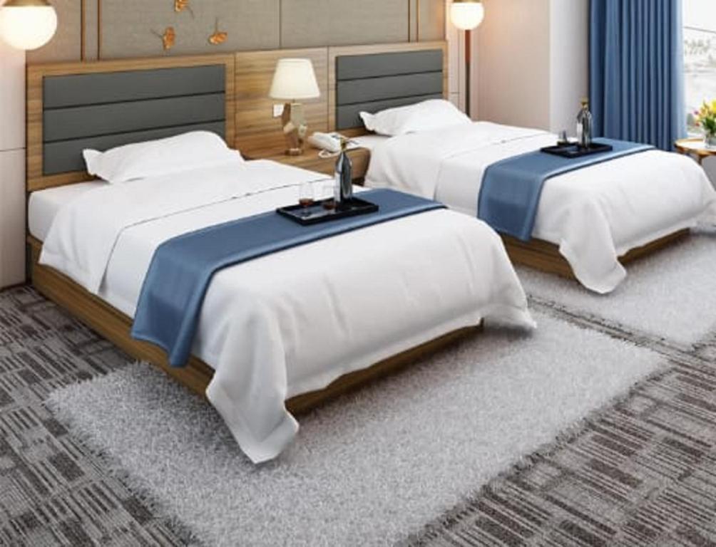 开罗Up Town Hotel的配有白色床单的酒店客房内的两张床