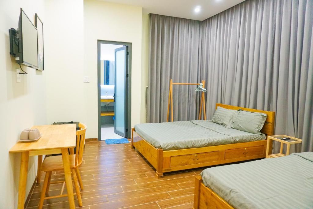 莲三TUY HOA CASA的一间卧室配有两张床、一张桌子和一张书桌
