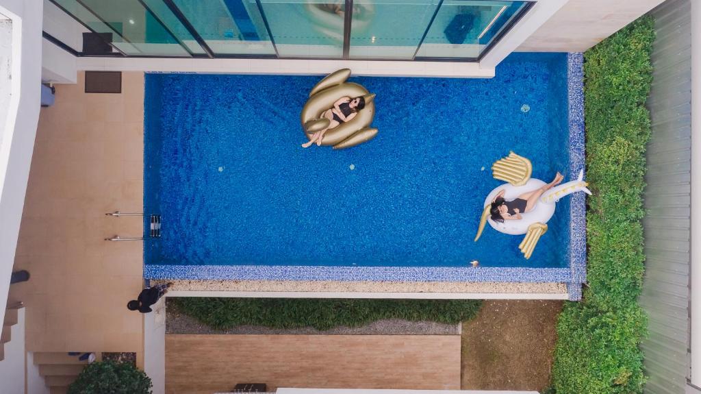 纳仲天Movenpick Pool Villa by Hello Pattaya的一张画,画着两个人在游泳池游泳