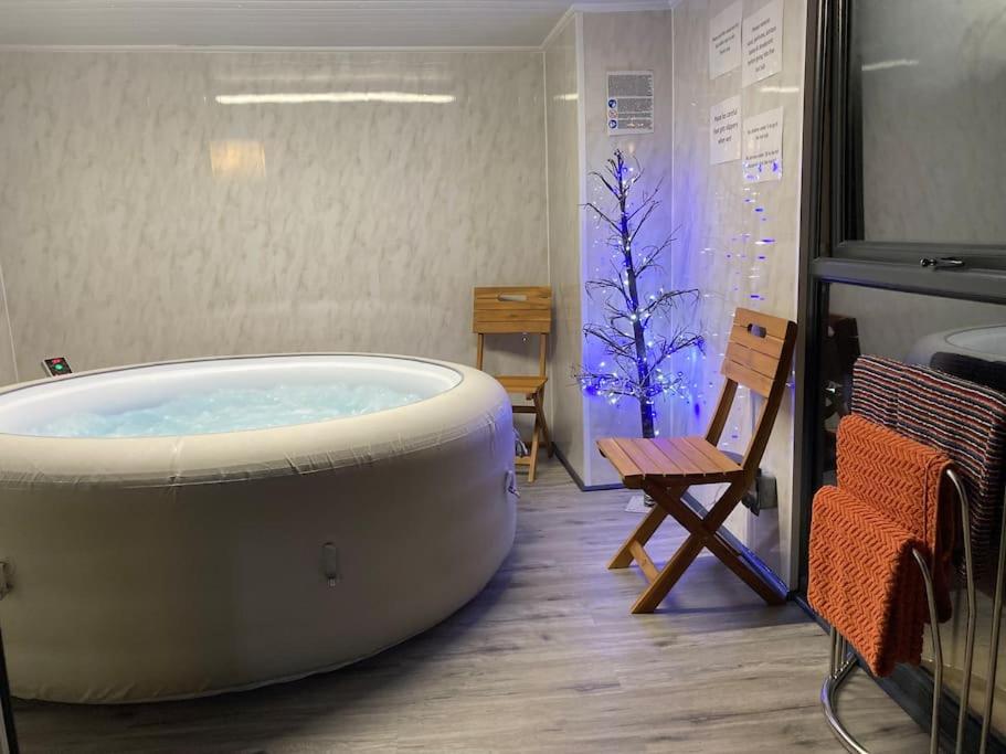 普利斯坦丁17 Cheerful 2 bed bungalow, hot tub/gym/pool table的一个带椅子的房间的大浴缸