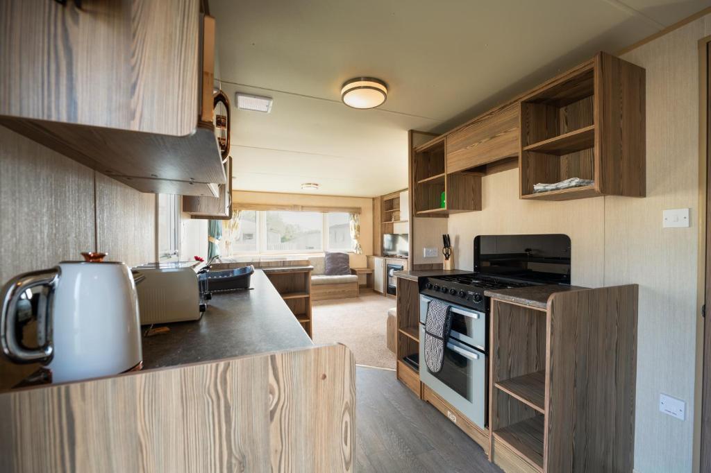 克利索普斯Waterside, Thorpe Park Cleethorpes Static Caravan的厨房配有木制橱柜和炉灶烤箱。