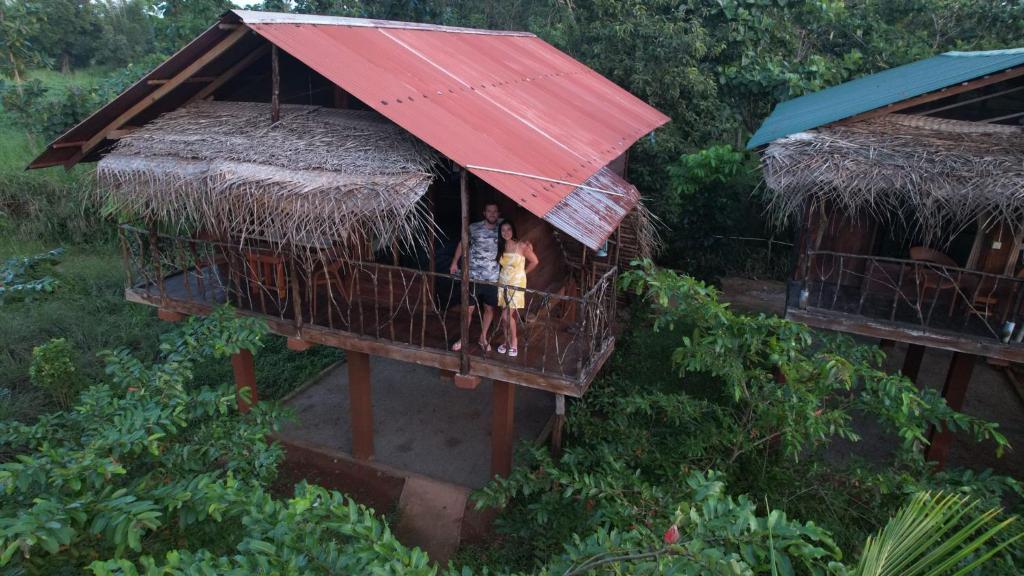 锡吉里亚Chena Huts Eco Resort的两人站在一个红色屋顶的房屋阳台