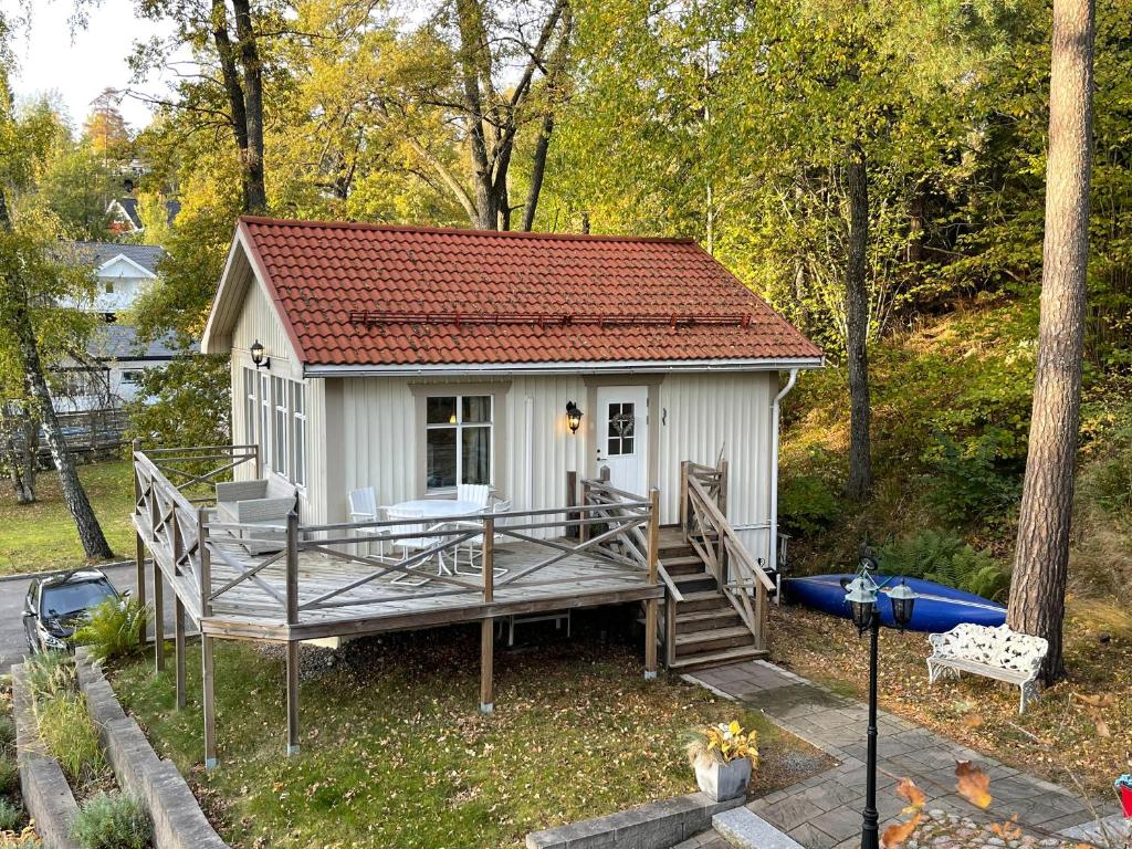TyresöCozy cabin, neighbour to lake & national park的一座白色的小房子,设有甲板和小船