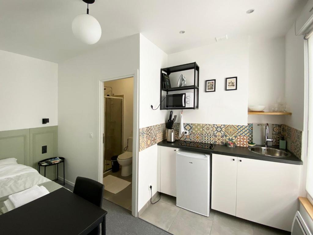 里摩日VILLA VLAS - Chambre d'Hôte - Limoges的厨房配有白色橱柜、水槽和床。