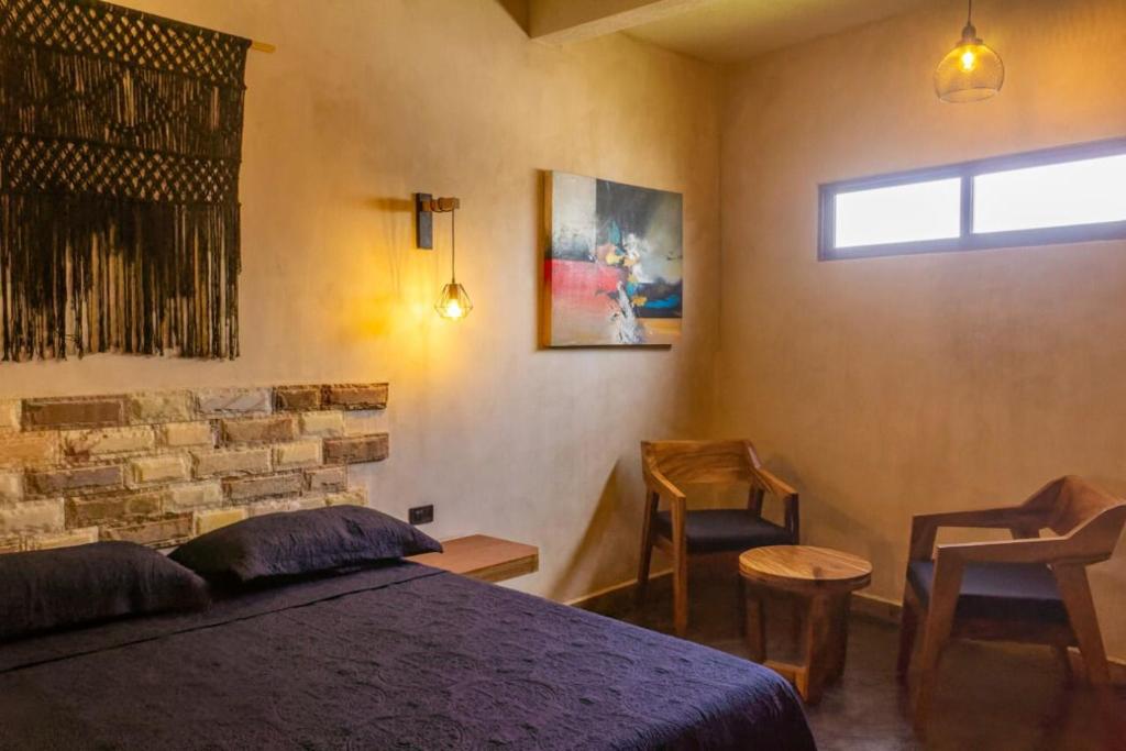 Cárdenasrelax hotelito的一间卧室配有一张床、两把椅子和一个窗户