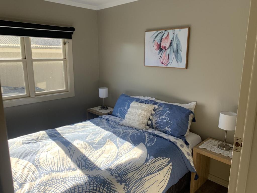 WedderburnWedderburn Farm Stay的一间卧室配有一张带蓝色棉被的床和窗户。