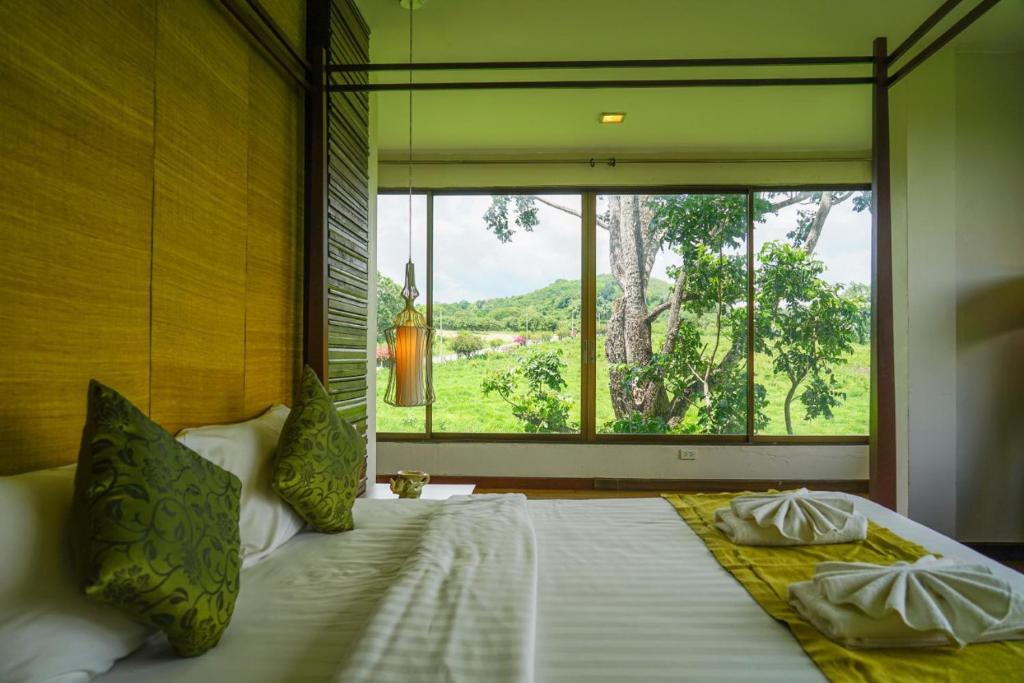 Ban Khanong Phra Taiโรงแรมวิลลา พาราดี的一间卧室设有一张大床和大窗户