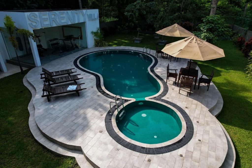 锡吉里亚Serenity Villa Dambulla的一个带椅子和遮阳伞的游泳池