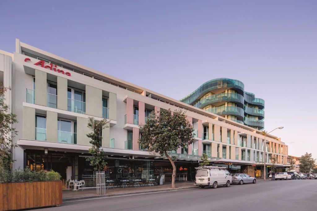 悉尼悉尼邦迪海滩阿迪娜公寓式酒店的街道上的建筑物,前面有车辆停放