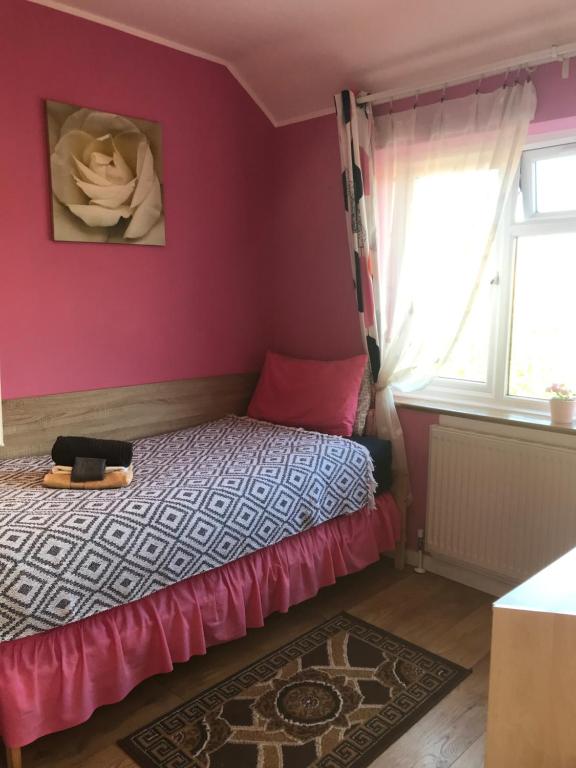 达格纳姆Becontreelodge的一间卧室配有一张粉红色的墙壁和窗户。