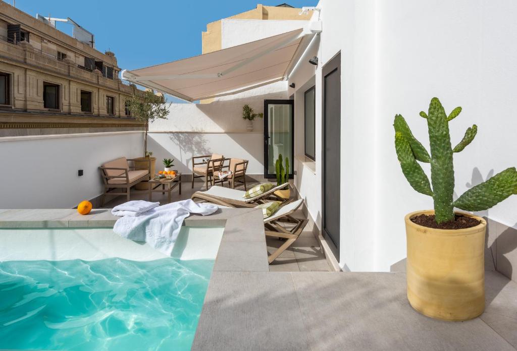塞维利亚Magno Apartments Cabo Noval Luxury House的一座带游泳池和仙人掌的房子