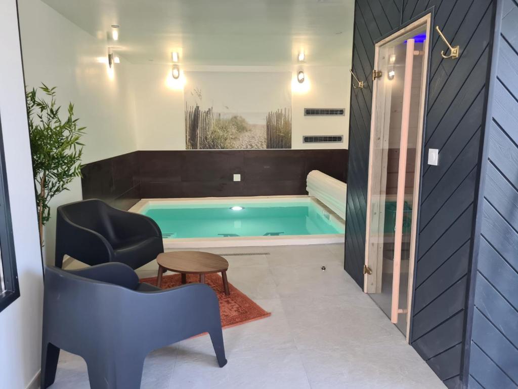 桑泰克Les Suites du Dossen的浴室设有游泳池、椅子和桌子