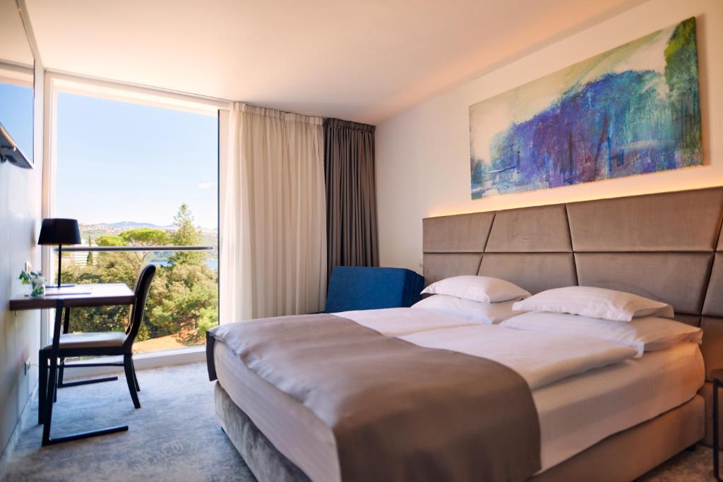 奥帕提亚Hotel Paris的配有一张床、一张书桌和一扇窗户的酒店客房