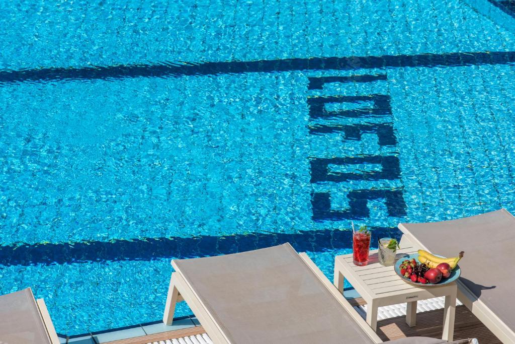 赫索尼索斯罗福思公寓酒店的一个带两把椅子和一碗水果的游泳池