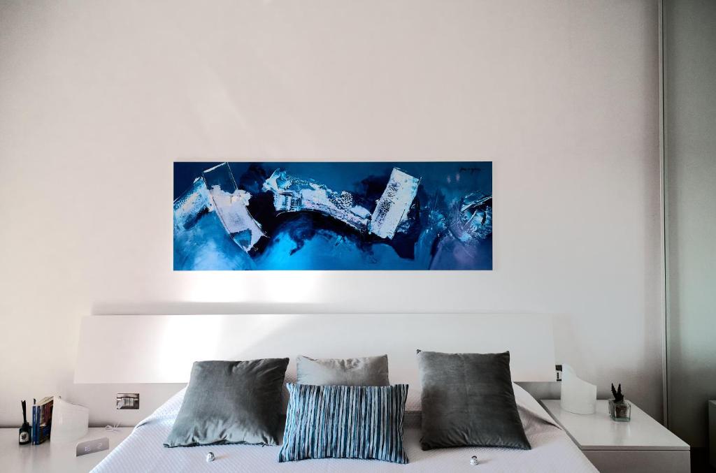 米兰San Siro Design Apartment的卧室配有白色床,墙上挂有蓝色画作