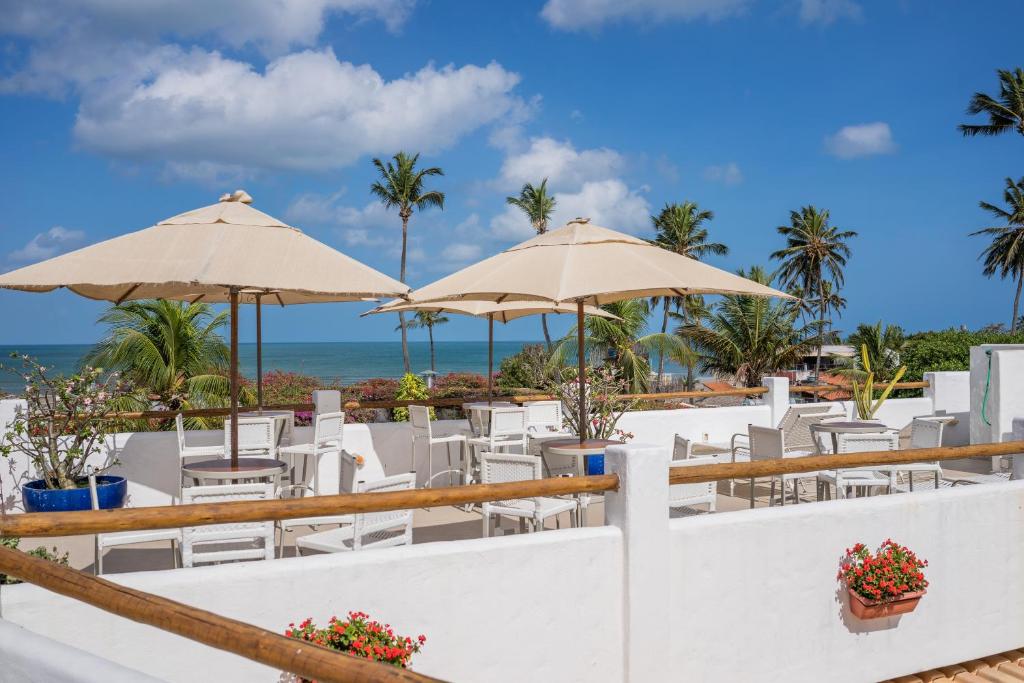 杰里科科拉Pousada Chez Toi的海滩上设有1间带椅子和遮阳伞的餐厅