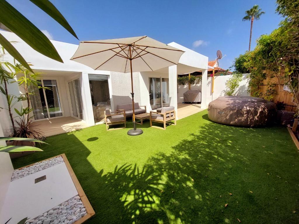 圣巴托洛梅Bungalow de diseño hidromasajes terraza y piscina.的一个带遮阳伞和椅子的庭院和一个草坪