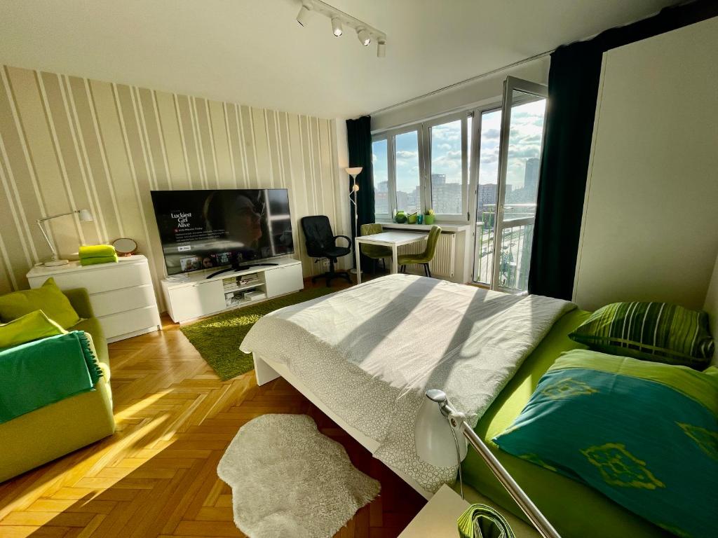 华沙Super Apartament GREEN Rondo ONZ Metro NOWE Wifi 300 Mb/s AirCondition Netflix Spotify的一间卧室配有一张床、一台电视和一张书桌