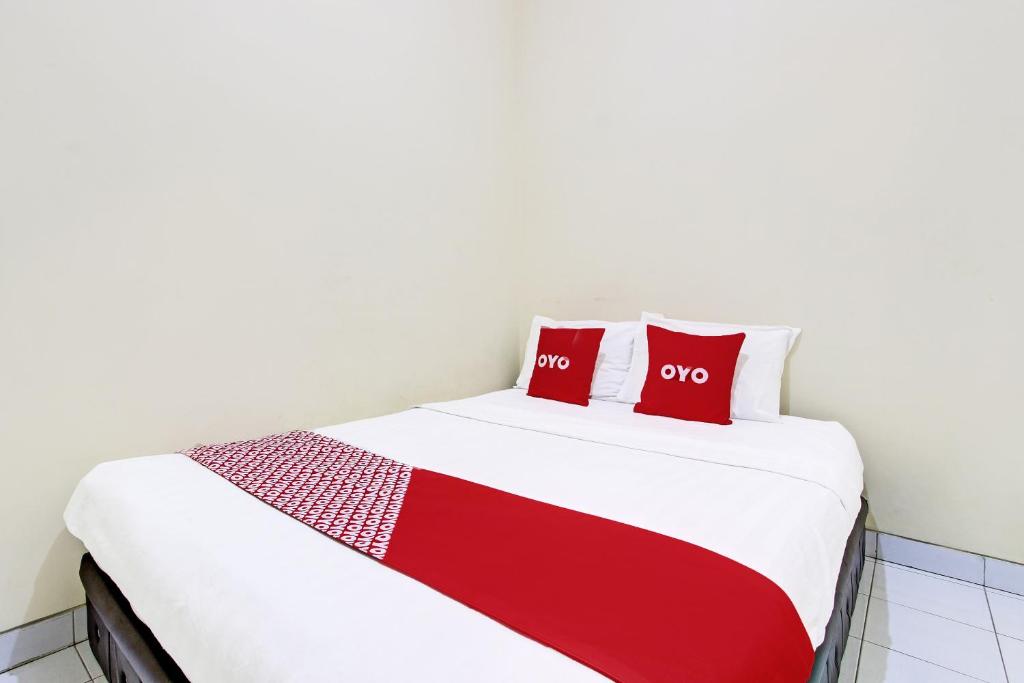 日惹OYO 91803 Gita Graha Guest House Syariah的床上有两个红色枕头的床