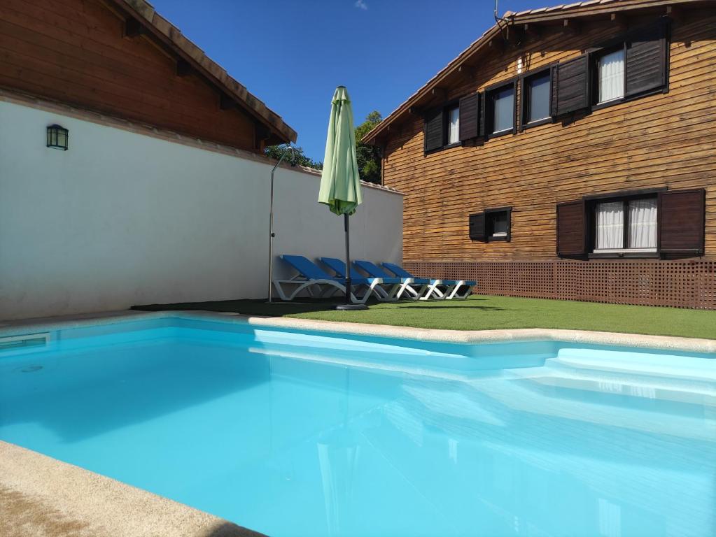 CobisaCasa Rural La Dehesa de Toledo a 5 minutos de Puy du Fou España的一座房子旁带遮阳伞的游泳池