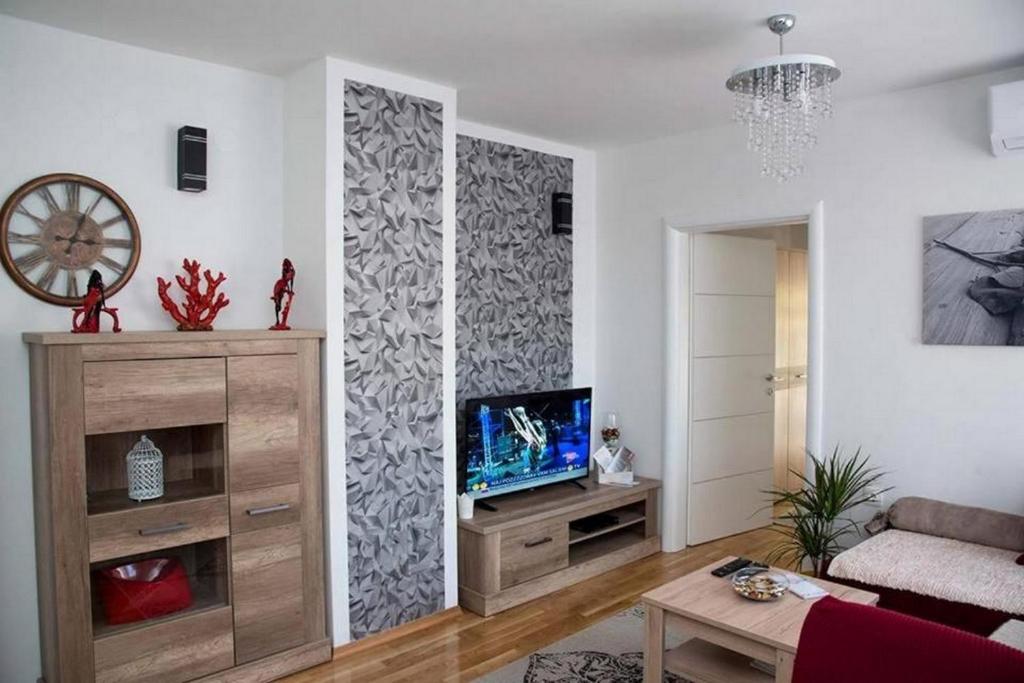 达鲁瓦尔Apartments Oaza的客厅配有电视和带阿里雅瓦手稿的墙壁。