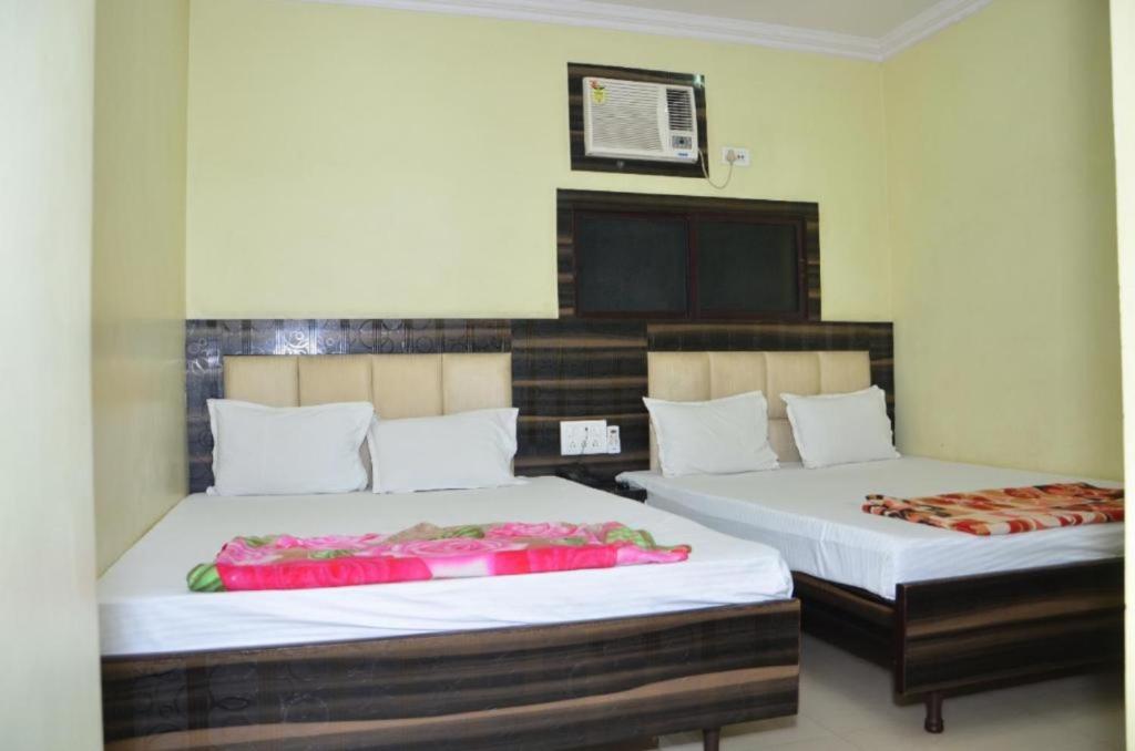HowrahGoroomgo Dev Guest House Howrah, Kolkata的客房内的两张床,上面有粉红色的鲜花