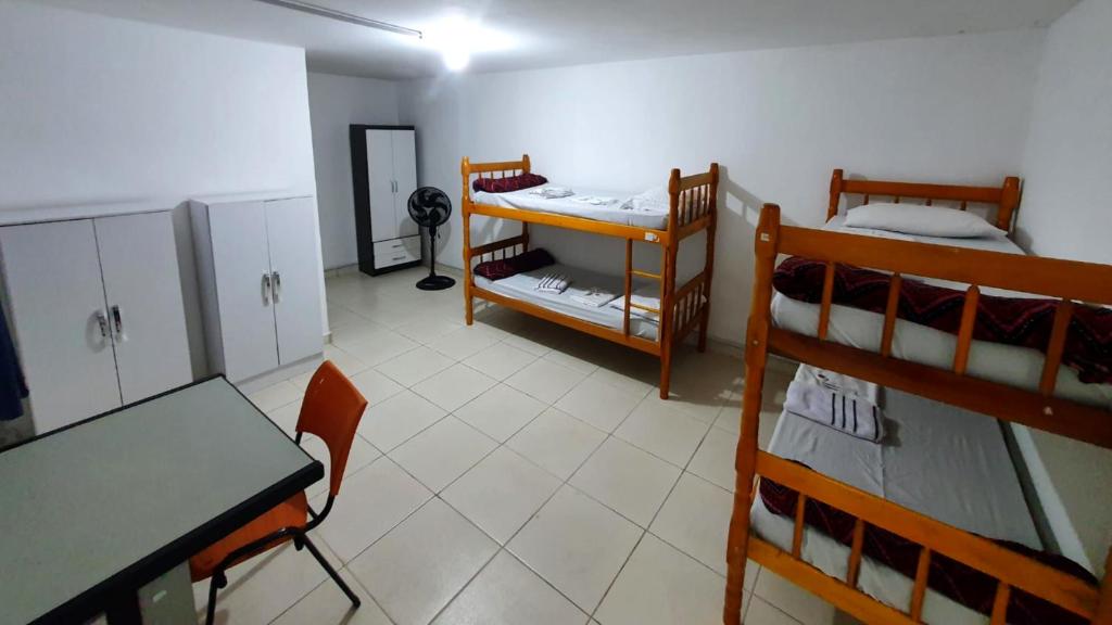 圣保罗Hostel Airport Rooms的客房设有一张桌子和两张双层床。