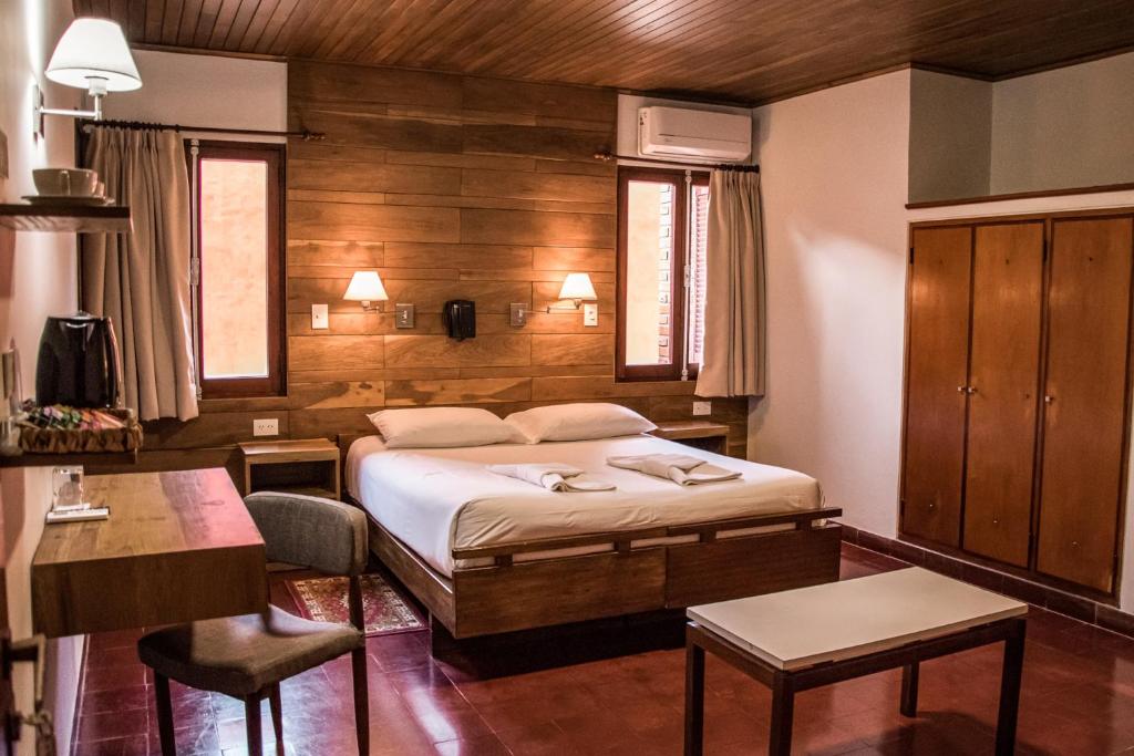 奥韦拉Hotel Cuatro Pinos的卧室配有一张床和一张桌子及椅子
