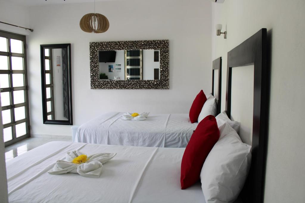 巴卡拉尔Casa Zazil的一间卧室配有两张带红色枕头和镜子的床