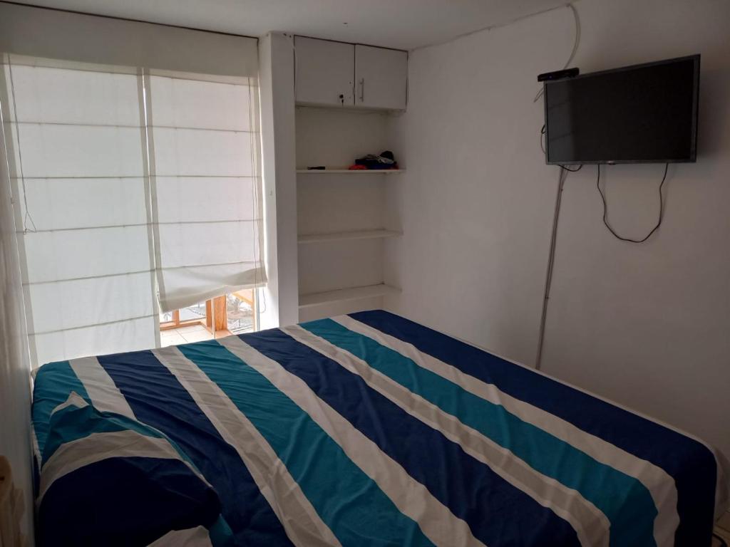 圣巴托洛Minidepartamento en San Bartolo - VISTA AL MAR的一间卧室配有一张带条纹毯子的床和一台电视