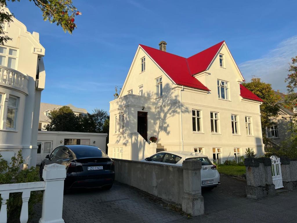 雷克雅未克Reykjavik Urban Escape 2-Bedroom Haven with Private Entrance的一座白色房子,屋顶红色,前面停有两辆车