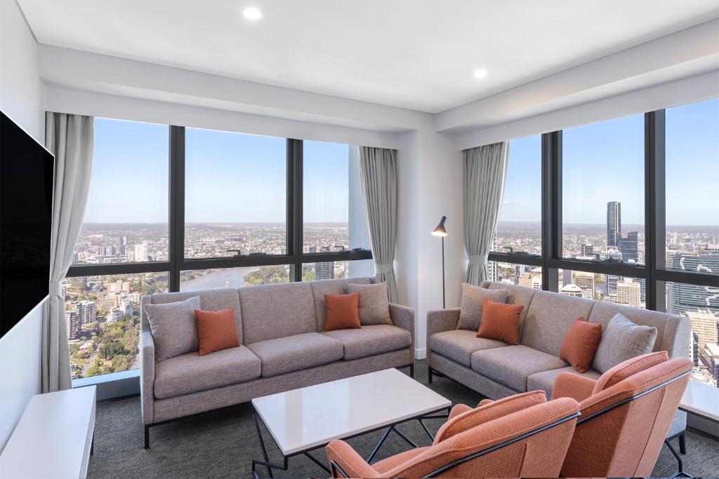 布里斯班Meriton Suites Adelaide Street, Brisbane的带沙发和椅子的客厅以及大窗户。
