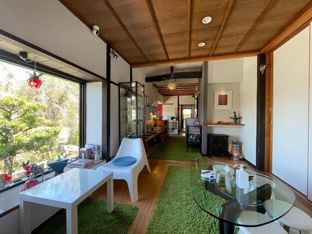直岛町Bamboo Village Guest House的一间带玻璃桌的客厅和一间房间
