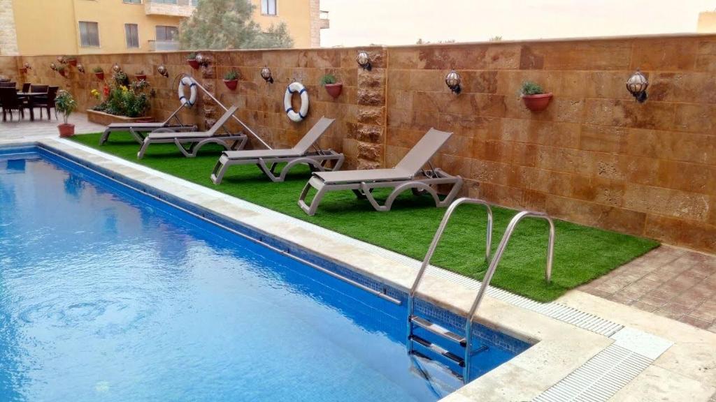 索瓦马مشروع ميريت البحر الميت السكني العائلي的一个带躺椅的游泳池,位于墙上