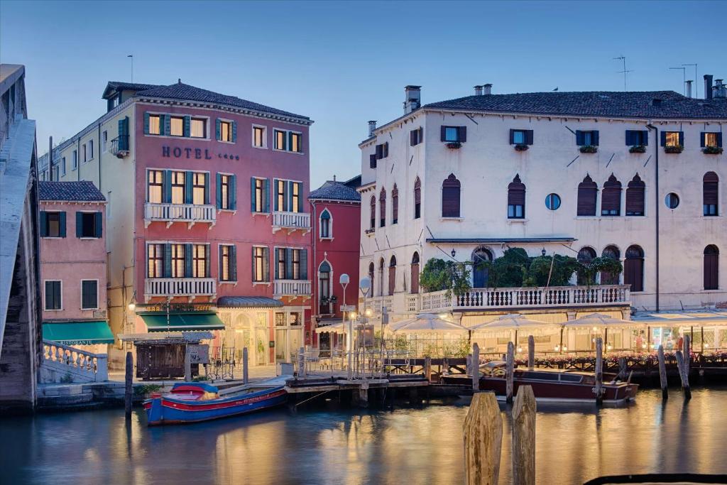 威尼斯NH Venezia Santa Lucia的运河旁的一群建筑物,有船